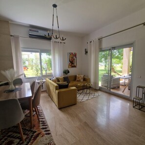 A spacious living area with a sofa, dining table, chairs, and a large sliding glass door leading to an outdoor patio. - Villa joudia Royal golf Fès (Fès)
