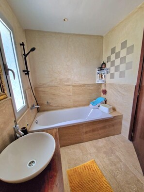 A bathroom with a bathtub, a sink, a shower, and a towel rack. - Villa joudia Royal golf Fès (Fès)