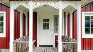 Ein rotes Gebäude mit einer weißen Veranda und einer weißen Tür.