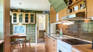 Eine Küche mit Holzausstattung, Fliesenrückwand, Herd und einem Essbereich mit Stühlen und Tisch.