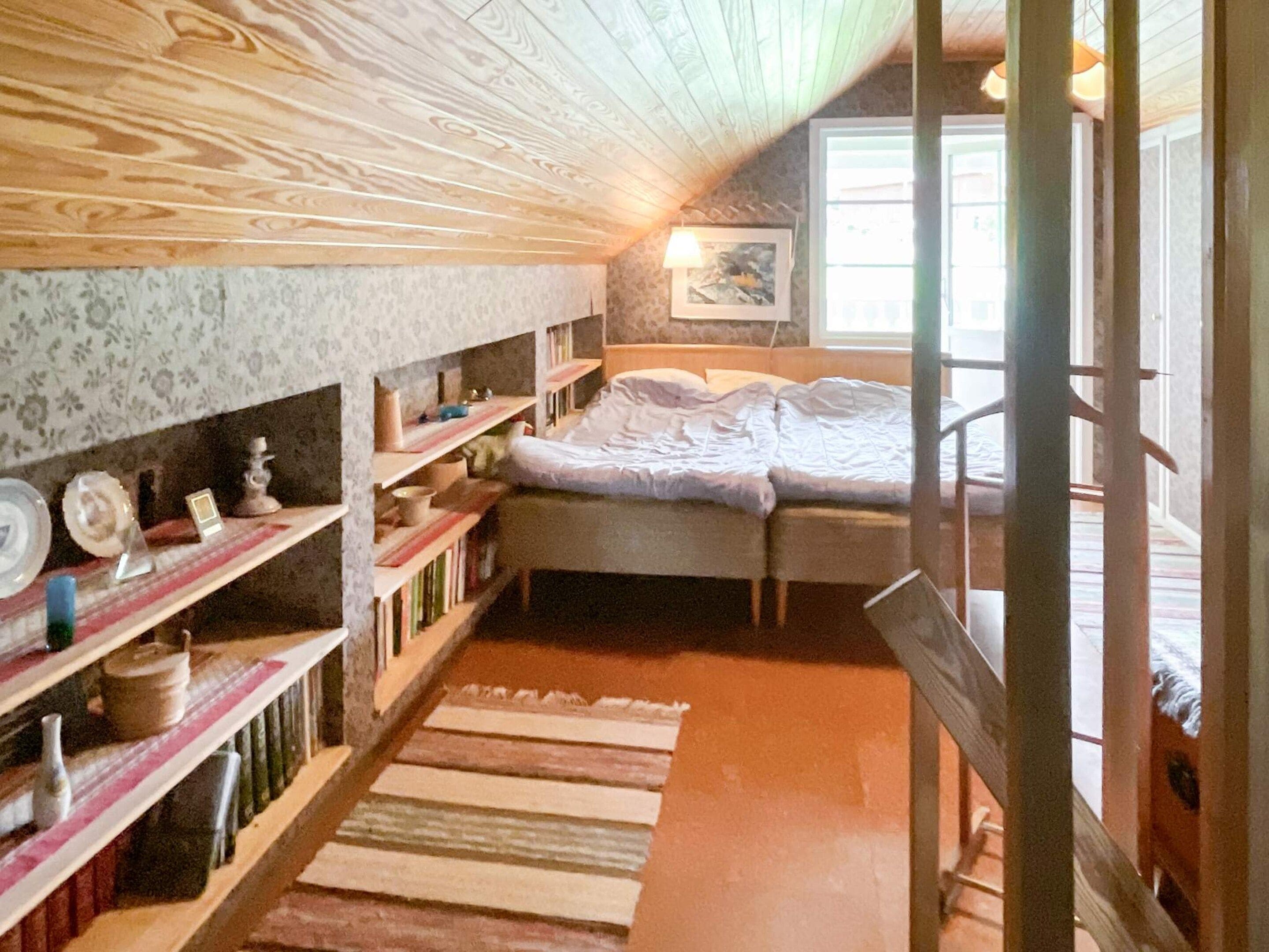 A bedroom with a bed, wooden shelves, and a window.