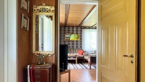 Ein Flur mit einer Holztür, einem Spiegel, einem kleinen Tisch mit einer Vase und einer Wand mit Muster.