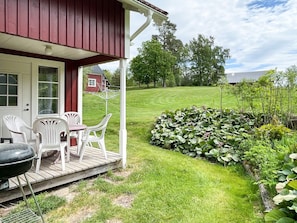 A red building with a porch, white chairs, and a grill. - 5 Person Holiday Home in Kristdala (Kristdala)
