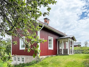 A red wooden house with a stone foundation, a porch, and a chimney. - 5 Person Holiday Home in Kristdala (Kristdala)