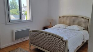 Ett sovrum med en säng, ett element, ett fönster och ett nattduksbord med en lampa.