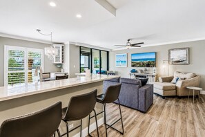 Eine moderne Küche mit Barbereich, Essbereich und Wohnbereich mit Sofa und Sesseln.