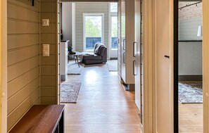 Un couloir mène à un espace de vie comprenant un canapé, une table basse et un tapis.