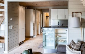 Eine moderne Küche mit einem Weinkühlschrank mit Glastür, Holzboden und einer gemütlichen Sitzecke mit Sofa und Kissen.