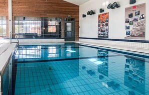 Ein Schwimmbecken mit hellblauen Fliesen, einer Holzverkleidung und einer Tür mit einem Schild darüber.