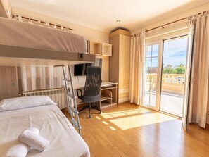 A hotel room with a bunk bed, a desk, a chair, a TV, and a balcony with a view. - Villa Mariela by NPMallorca (Sa Coma)