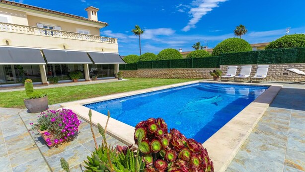 A swimming pool with a stone deck, surrounded by a well-maintained lawn and a stone wall. - Villa Mariela by NPMallorca (Sa Coma)