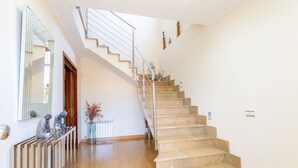A staircase with beige steps and a metal railing, leading to an upper floor. - Villa Mariela by NPMallorca (Sa Coma)