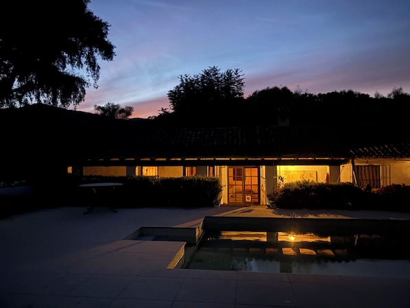 A traditional building with a tiled roof, a central courtyard, and a small pool.