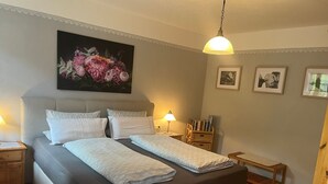 Un dormitorio con una cama grande, mesitas de noche, un banco y un cuadro colgado en la pared.