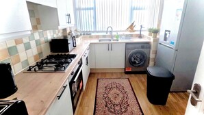 Una cocina compacta con estufa a gas, lavadora y refrigerador.