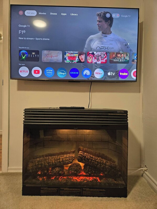 A television mounted on a wall displaying a streaming service interface with various app icons.