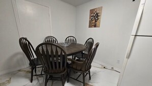 Ein Essbereich mit Marmorboden, einem weißen Kühlschrank und einem Gemälde an der Wand.