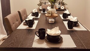 Ein Esstisch, gedeckt mit schwarzen Tassen, weißen Servietten und einer Tischdekoration mit einer Pflanze.