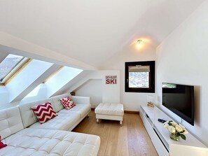 Ein modernes Schlafzimmer im Loft-Stil mit Oberlichtern, einer Couch, einem kleinen Tisch, einem Fernseher und einem Schild an der Wand.