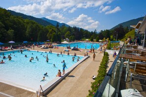 A large outdoor swimming pool with multiple lanes, surrounded by a deck area with chairs and umbrellas. - Charming Duplex for 4 in the Heart of Morzine (MORZINE)