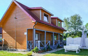 Ein zweistöckiges Holzhaus mit einer Veranda und einer überdachten Außenbereich-Sitzgruppe.
