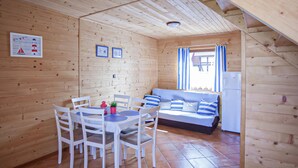 Una cabana de fusta amb menjador, un sofà i un frigorífic.