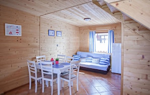 Eine Holzhütte mit Essbereich, einer Couch und einem Kühlschrank.