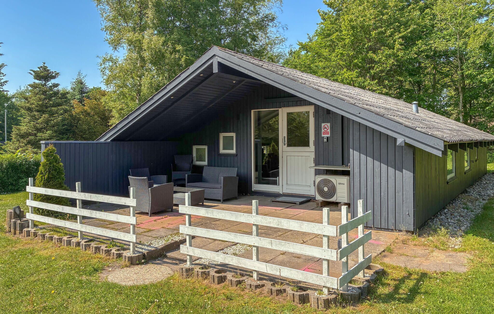 A small cabin with a porch, outdoor seating, and a door with a sign.