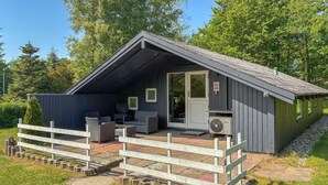 A small cabin with a porch, outdoor seating, and a door with a sign. - Stunning home in Toftlund with WiFi (Toftlund)
