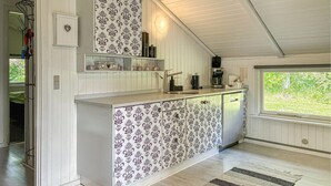 A kitchen with patterned wallpaper, a built-in sink, and a window with a view of greenery. - Stunning home in Toftlund with WiFi (Toftlund)