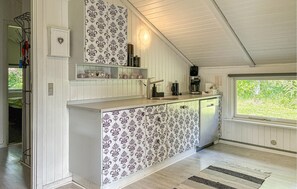 A kitchen with patterned wallpaper, a built-in sink, and a window with a view of greenery. - Stunning home in Toftlund with WiFi (Toftlund)