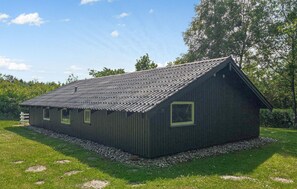 A wooden cabin with a sloped roof, surrounded by a gravel path and lush greenery. - Stunning home in Toftlund with WiFi (Toftlund)