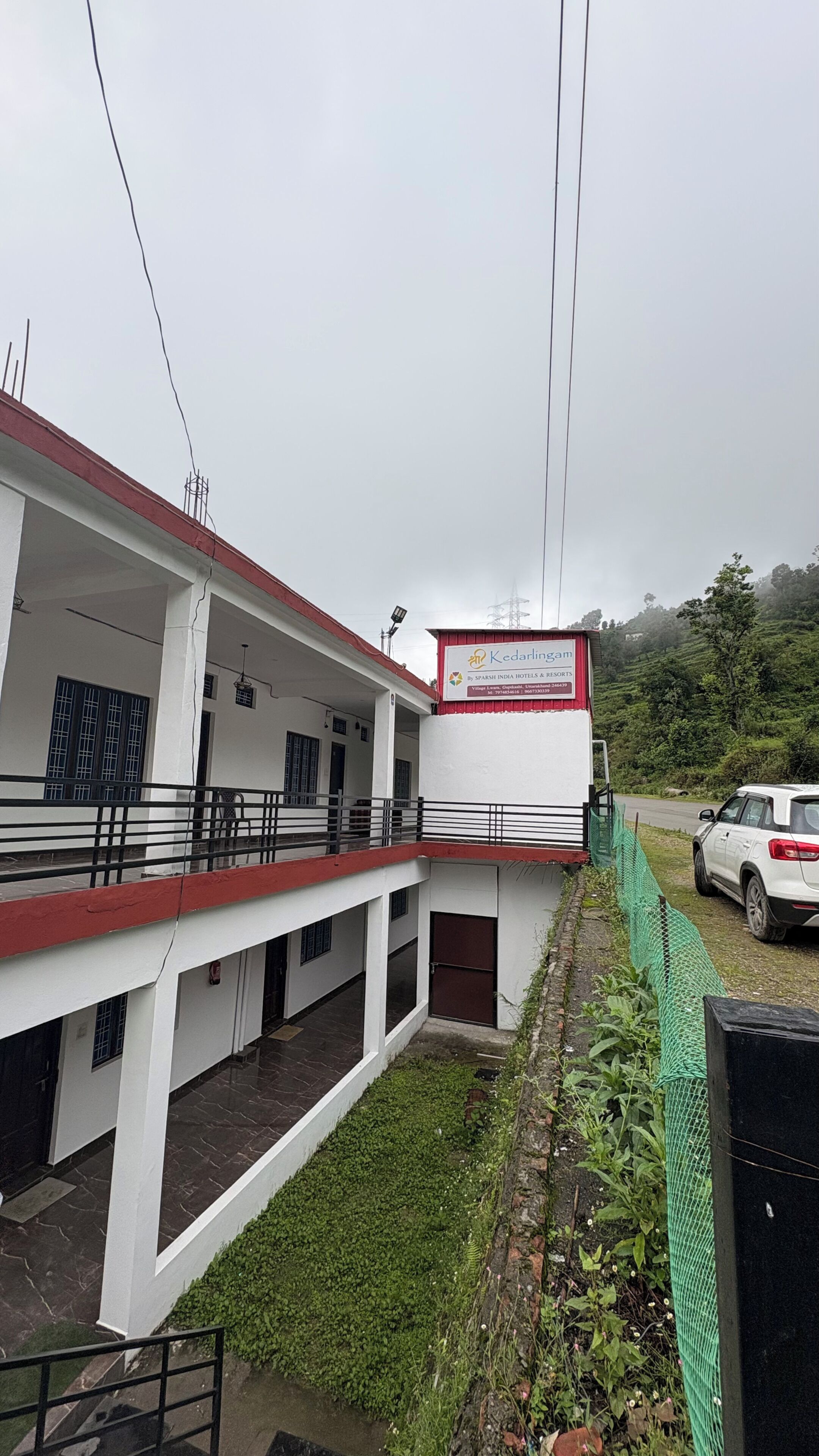Un edificio con fachada roja y blanca, un letrero y una cerca verde.