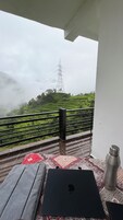 A balcony with a view of a green landscape and a power line tower.
