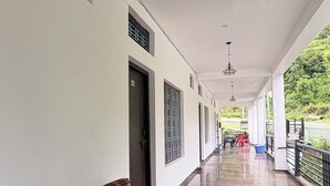 Um corredor coberto com sofá, portas e vista para área verde.
