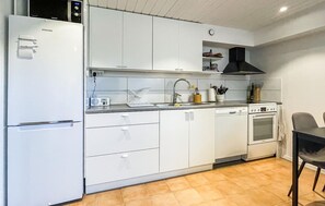 A modern kitchen with white cabinetry, a built-in oven, a dishwasher, and a microwave.