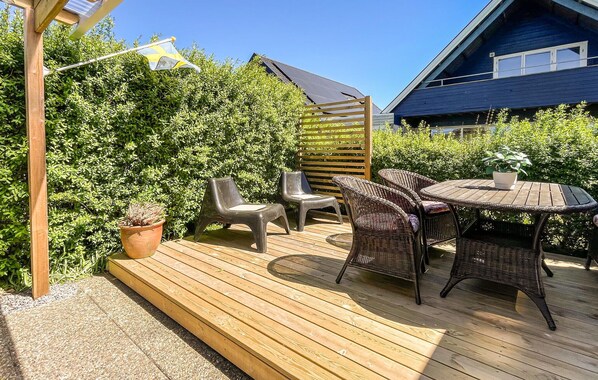 Eine HolzdTerrasse mit Gartenmöbeln, einer Pergola und einem Haus im Hintergrund.