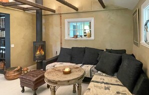 Ein gemütliches Wohnzimmer mit Kamin, einer Couch, einem Holztisch und einem Fenster mit Blick.