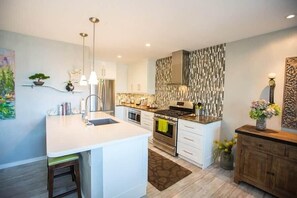 A modern kitchen with white cabinetry, stainless steel appliances, and a central island.