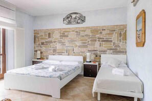 Ein Schlafzimmer mit Steinwand, zwei Betten, einem Nachttisch und einem Wandbild.