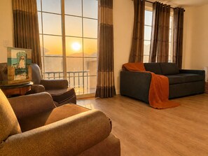Ein Wohnzimmer mit Sofa, Sessel und einem Gemälde auf einem Tisch.