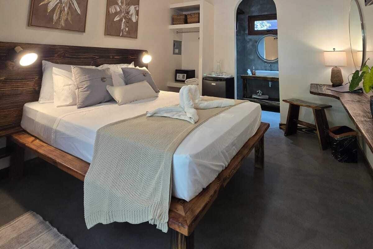 Un dormitorio con una cama de madera, un ventilador de techo y obras de arte en las paredes.
