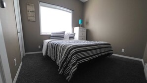 A bedroom with a bed, a window, a dresser, and a wall with a motivational quote. - Sleep & Grill | 5BR, Huge Yard, Smoker, BBQ (Fox Creek)