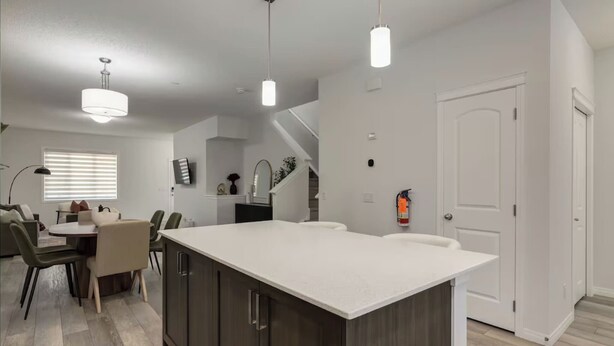 Una cocina moderna con una isla grande, luces colgantes y un comedor con mesa y sillas.