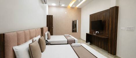 A hotel room with two beds, a TV, a ceiling fan, and recessed lighting.