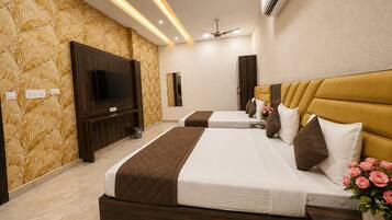 A hotel room with two beds, a television, a ceiling fan, and a wall-mounted air conditioner.