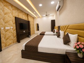 A hotel room with two beds, a television, a ceiling fan, and a wall-mounted air conditioner.