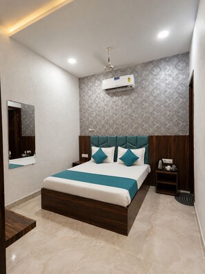 A modern bedroom with a bed, a nightstand, a mirror, and an air conditioning unit. - Hotel KR Near Golden Temple (Amritsar)
