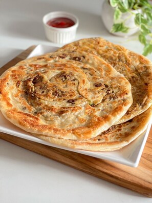 A plate of flatbreads with a side of red sauce. - Hotel KR Near Golden Temple (Amritsar)