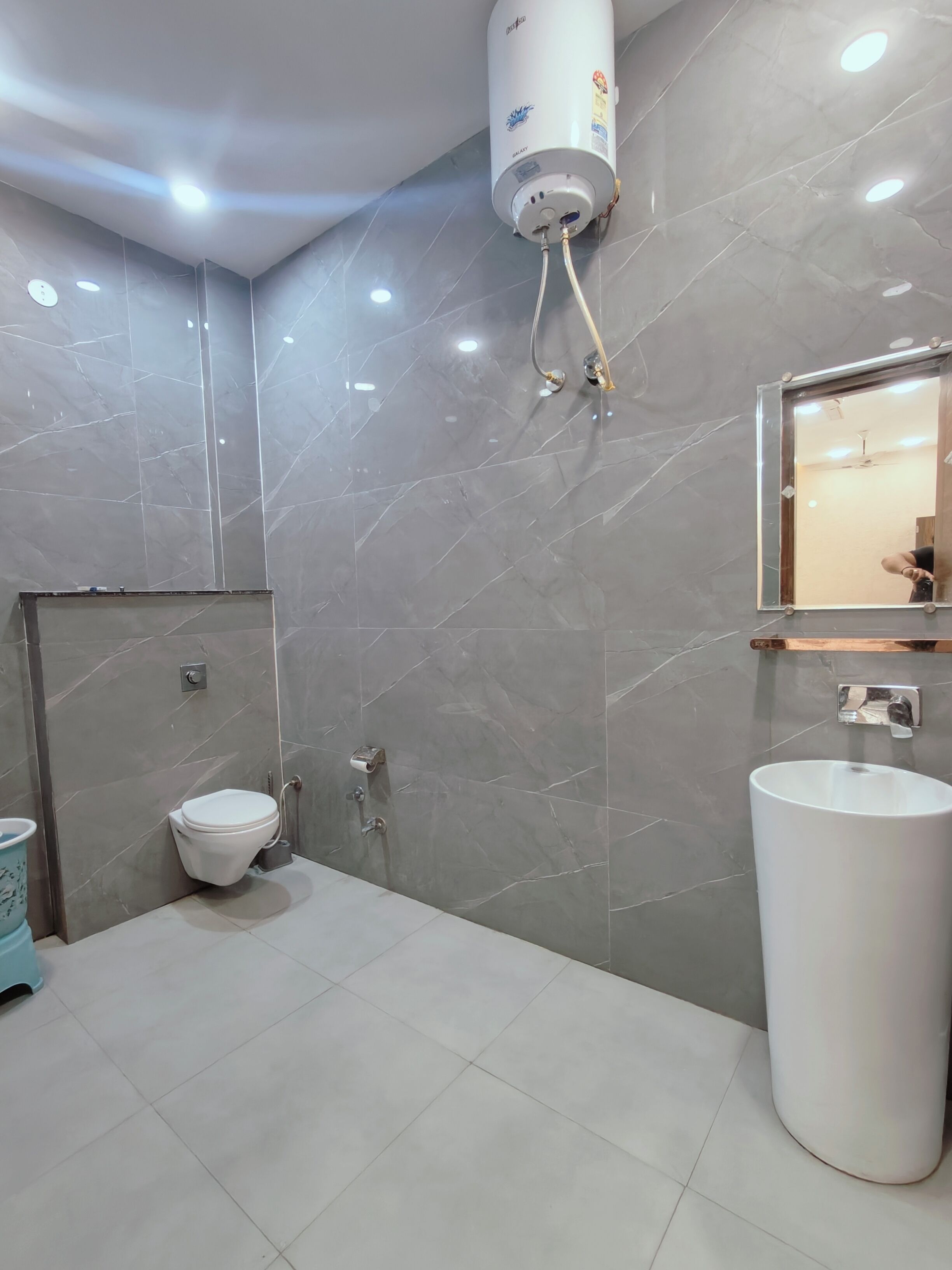 A bathroom with a toilet, sink, and water heater.